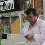 Proprietario di un tabacchi mostra un Gratta e Vinci vincente con un sorriso soddisfatto.