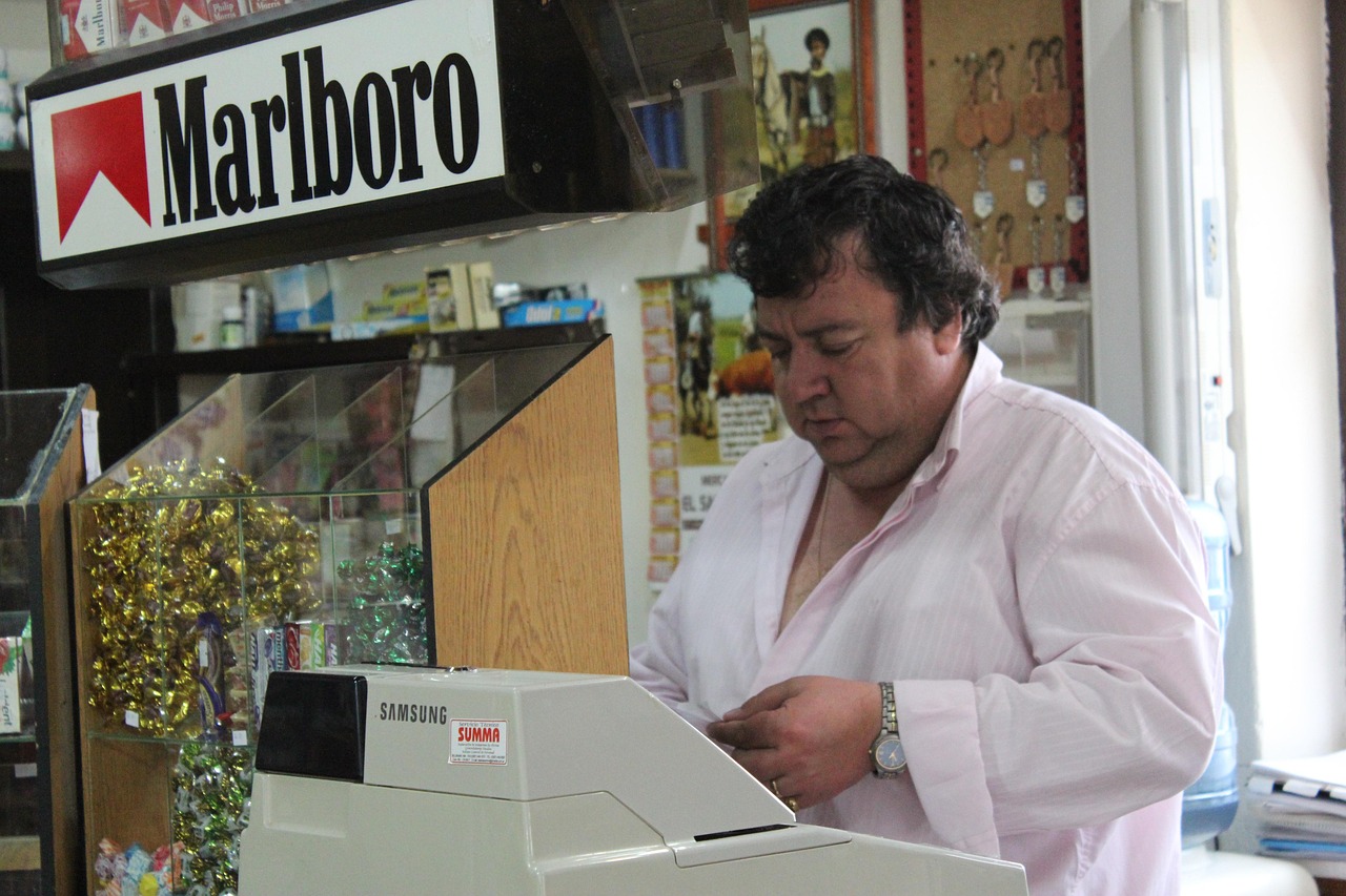 Proprietario di un tabacchi mostra un Gratta e Vinci vincente con un sorriso soddisfatto.